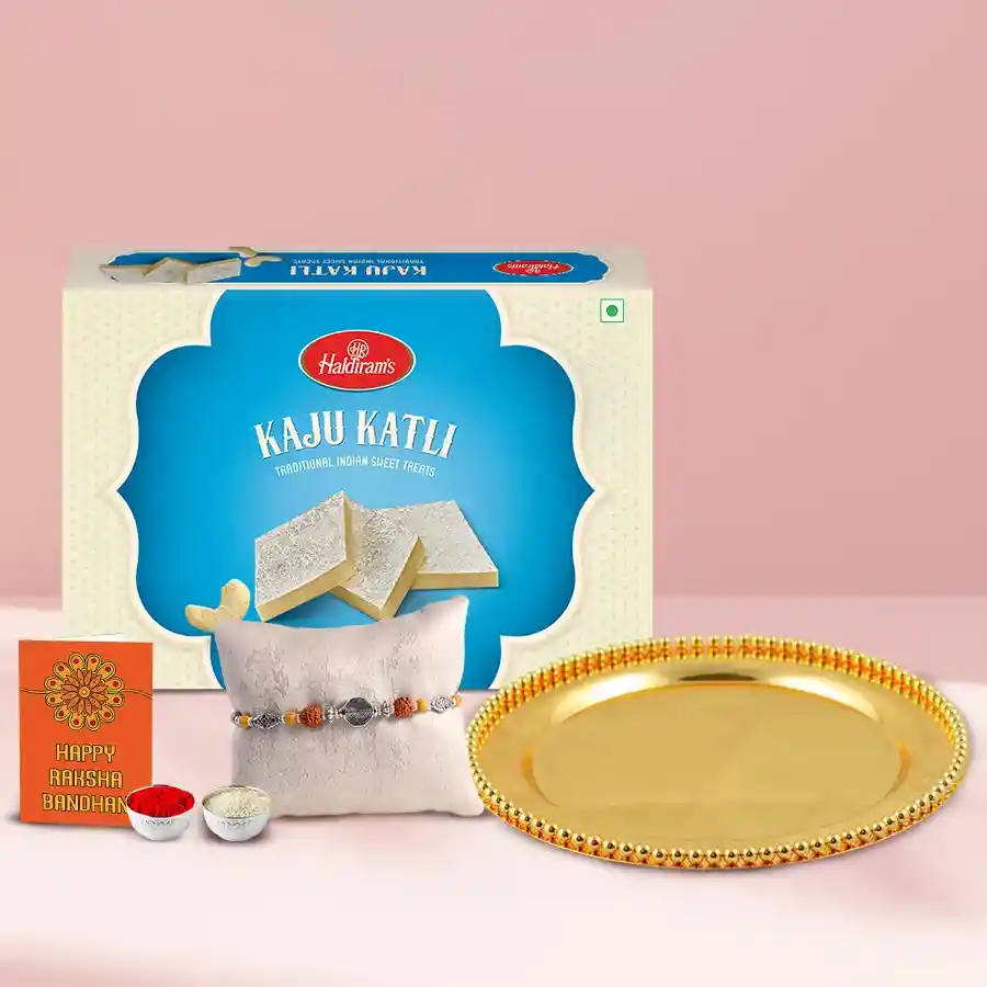 German Silver Golden Plated Thali with Kaju Katli from Haldirams and Rakhi, Roli, Tilak, and Chawal displayed for Raksha Bandhan celebration.