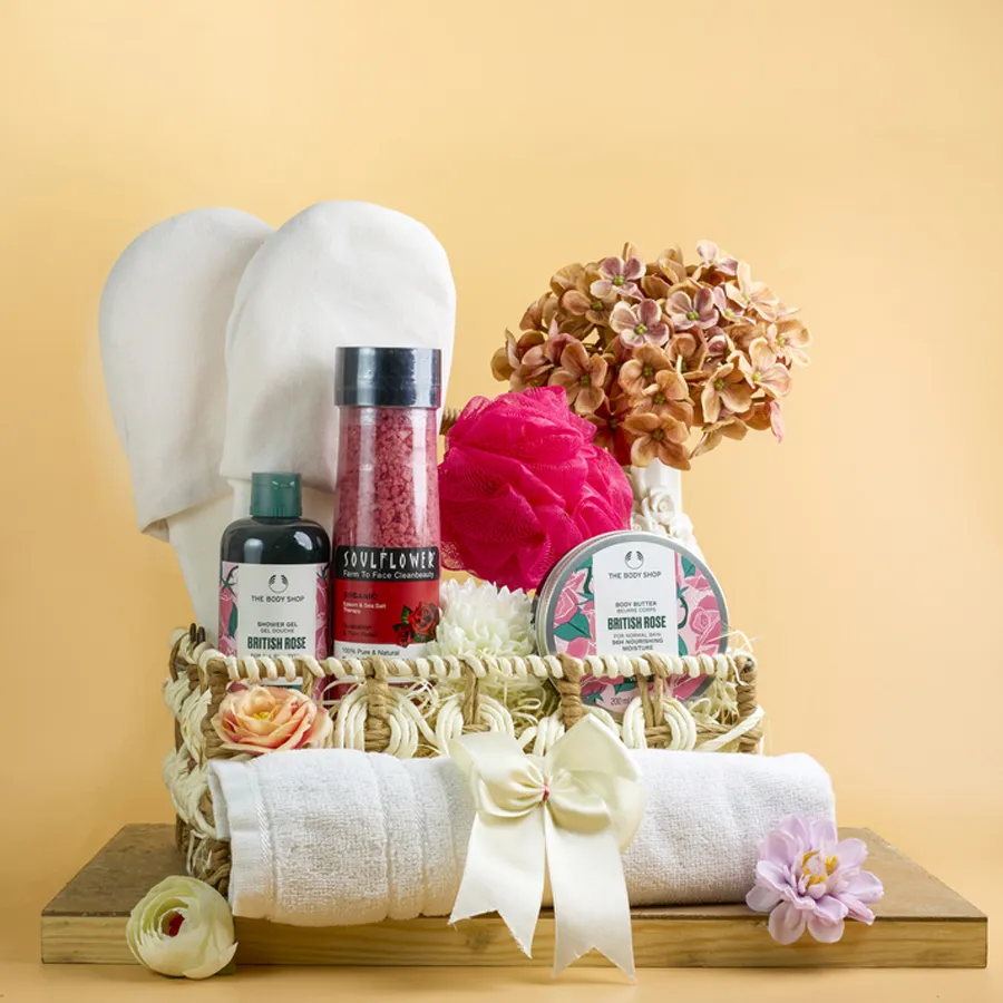 Ultimate British Rose Bathing Essentials Hamper featuring shower gel, body butter, loofah, disposable slippers, and plush towel in a designer basket