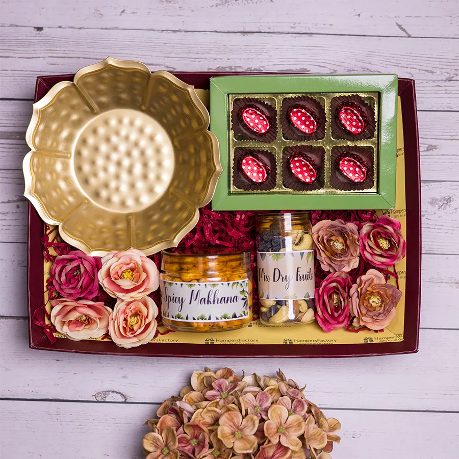 Elegant gift pack featuring a decorative Urli bowl, spicy makhana, a mix of dry fruits, and homemade chocolates in a stylish reusable tray.