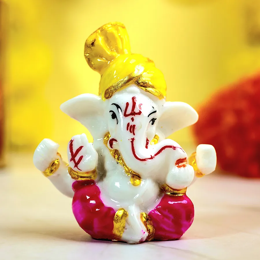 Handcrafted Mukut Ganesh idol with vibrant colors and intricate details, displayed on a decorative base.