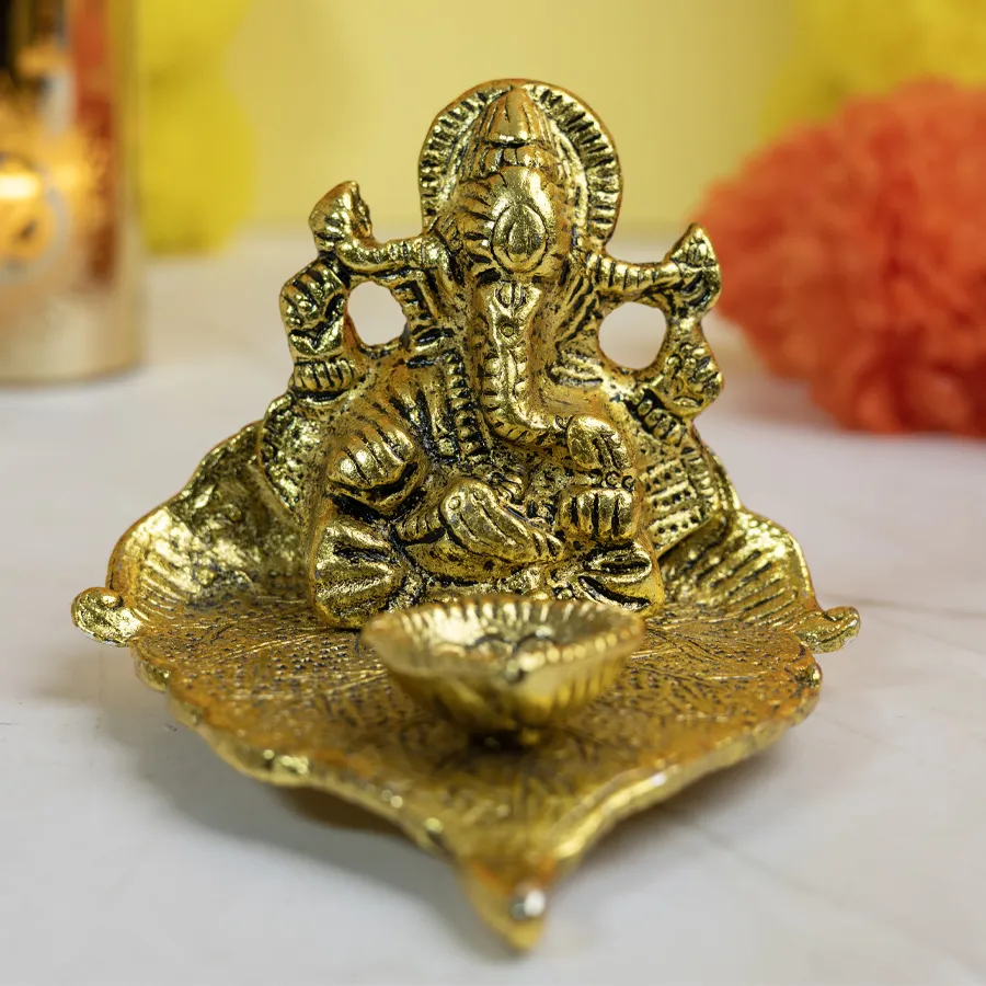 Brass Lord Ganesha idol on a crafted leaf with a diya, symbolizing abundance and harmony.