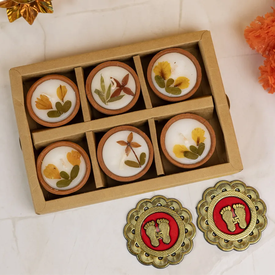 Natural terracotta candles with dry flowers and Laxmi Charan sticker combo on a decorative surface