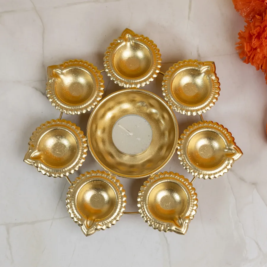 Diya shape urli bowl with floating candles and colorful petals, showcasing traditional decor elements