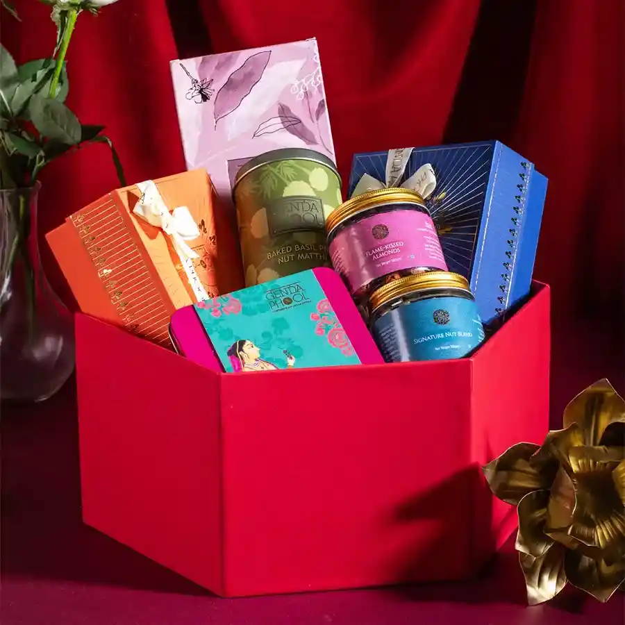 Nutty Bliss Gift Set featuring stuffed Medjool dates, figs, baked basil pine nut matthi, hazelnut chikki brittle, Mithai bites, flame-kissed almonds, and a signature nut blend arranged in a decorative box.