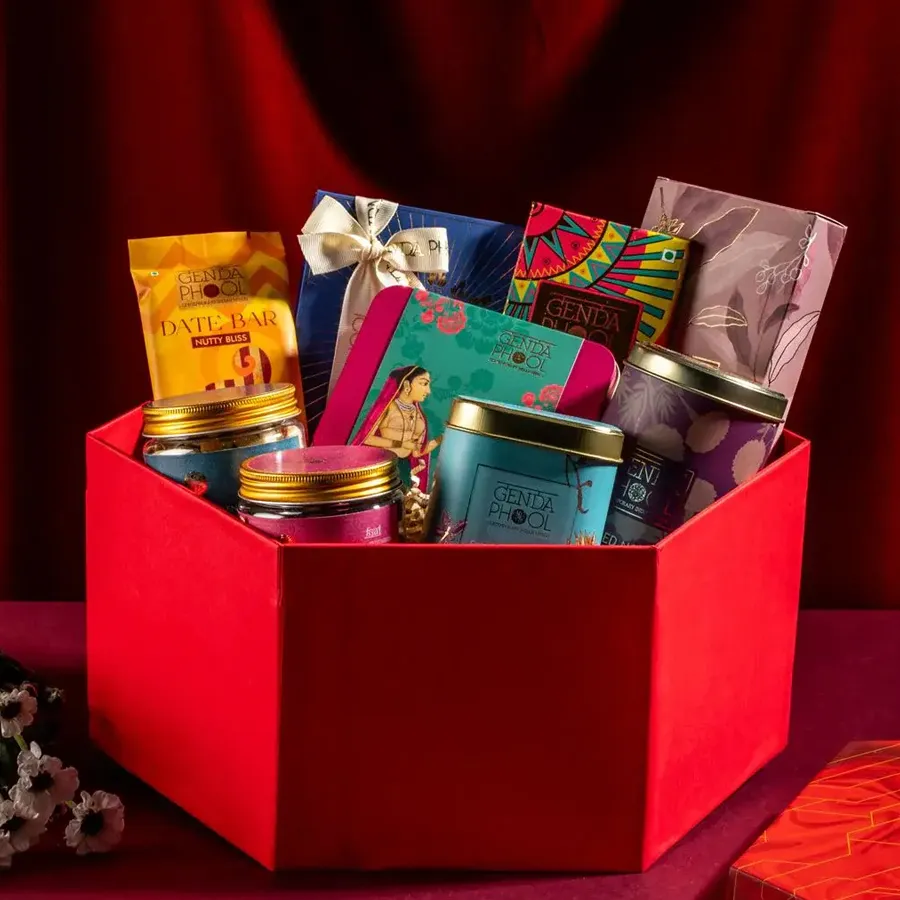 Nutty Indulgence Gift Box filled with treat items like Cashew & Gulkand Chikki, Nutty Bliss Date Bars, flame-kissed Almonds, stuffed figs, Mithai Bites, Baked Nolen Matthi, Hazelnut Brittle, Signature Nut Blend, and Coconut Almond Thins.