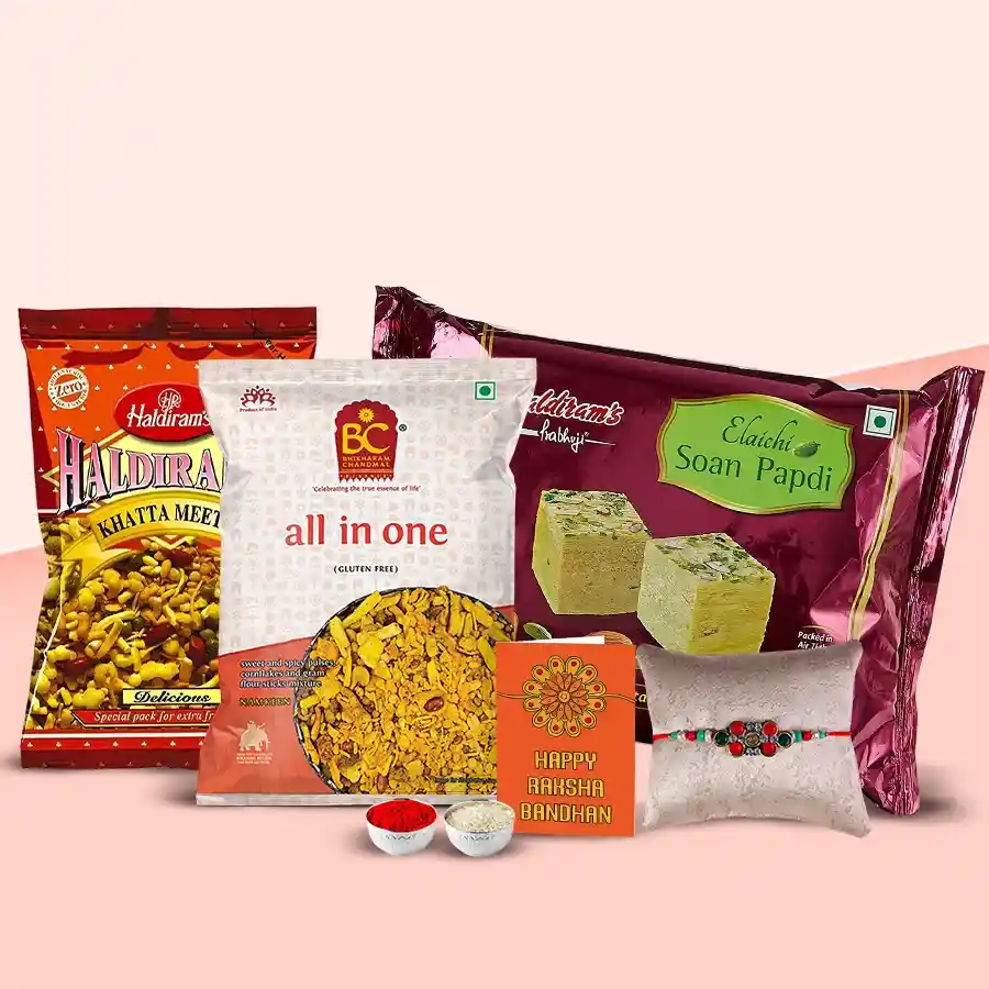 Gift pack featuring 400g Soan Papdi, 200g Khatta Mitha, 200g All In One Mixture, and a free Rakhi, arranged beautifully for Raksha Bandhan.