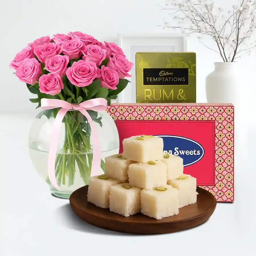 A beautiful gift combo featuring 10 pink roses in a glass vase, Cadbury Temptations Rum N Raisins, and 250 grams of Coconut Barfi.