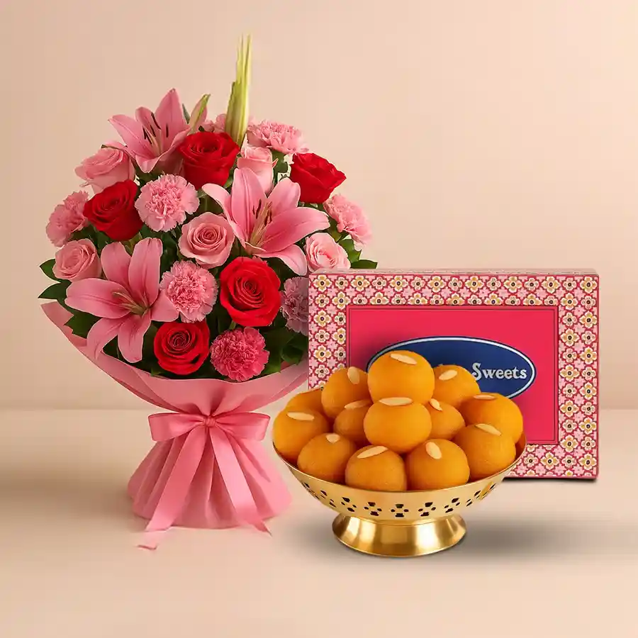 A charming gift set featuring a mixed flower bouquet with red and pink roses, pink carnations, and pink lilies, paired with Motichur Laddu sweets.