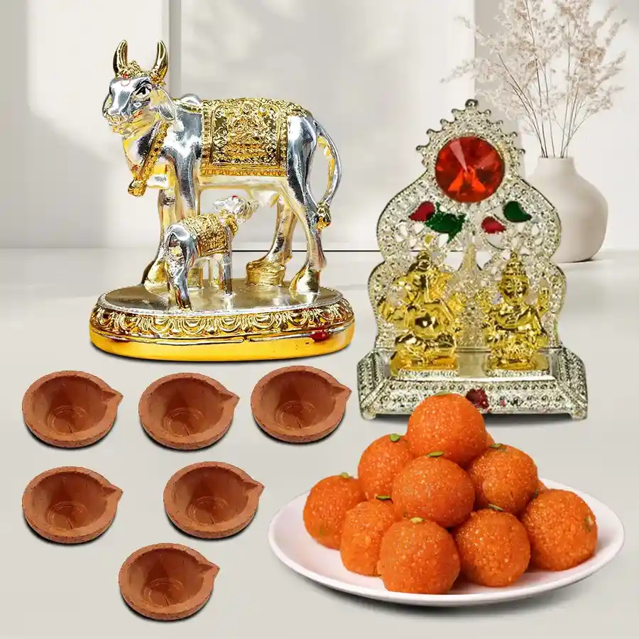Exquisite Pooja Combo Gift Set featuring a silver Kamdhenu Idol, Ganesh Laxmi Mandap, ladoos, and mud diyas.
