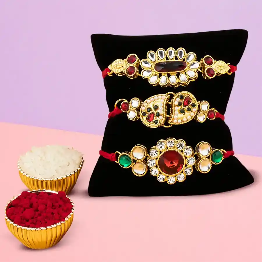 Set of 3 designer Rakhis with colorful thread designs, accompanied by a small container of Roli, Tilak, and Chawal, displayed on a decorative background.