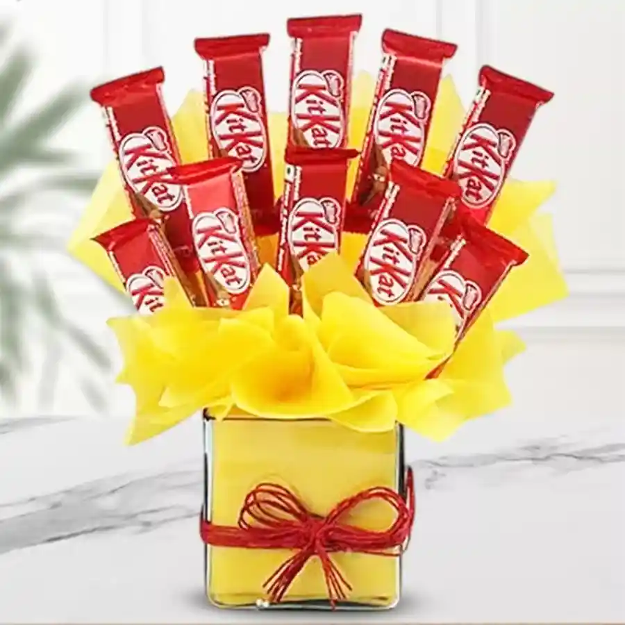 Arrangement of 10 Kitkat chocolates in a glass vase with yellow tissue wrapping.
