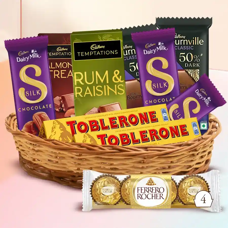 Ultimate Chocolate Indulgence Basket featuring Cadbury and Ferrero Rocher chocolates in a decorative cane basket.