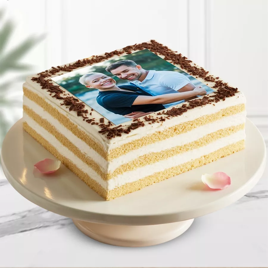 Square vanilla photo cake with cream frosting and chocolate flakes.