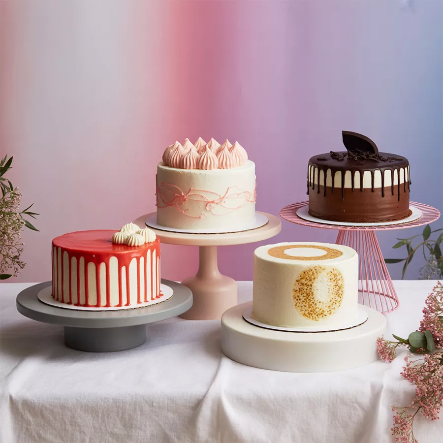 An assortment of four eggless round cakes, including red velvet, chocolate, strawberry, and crunchy butterscotch, beautifully presented for gifting.