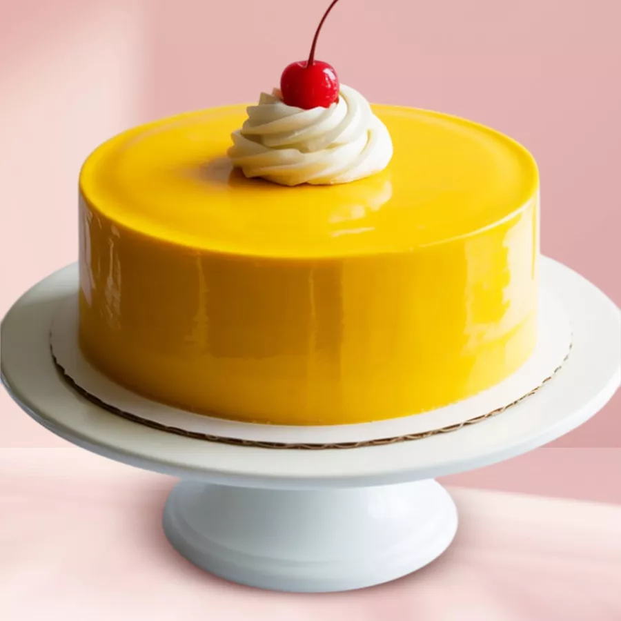 Tropical Mango Bliss Cake with vanilla sponge, mango syrup frosting, and cherry topping.