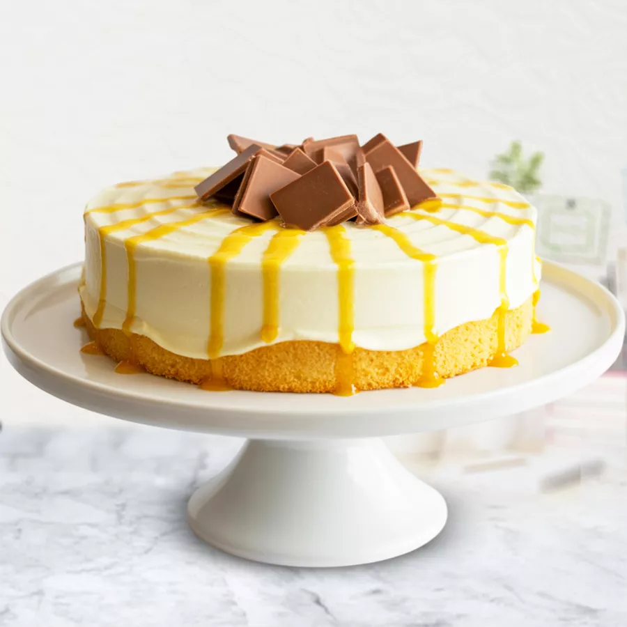 Eggless Mango Cake topped with chocolate thins and mango syrup, beautifully layered on a vanilla sponge base.