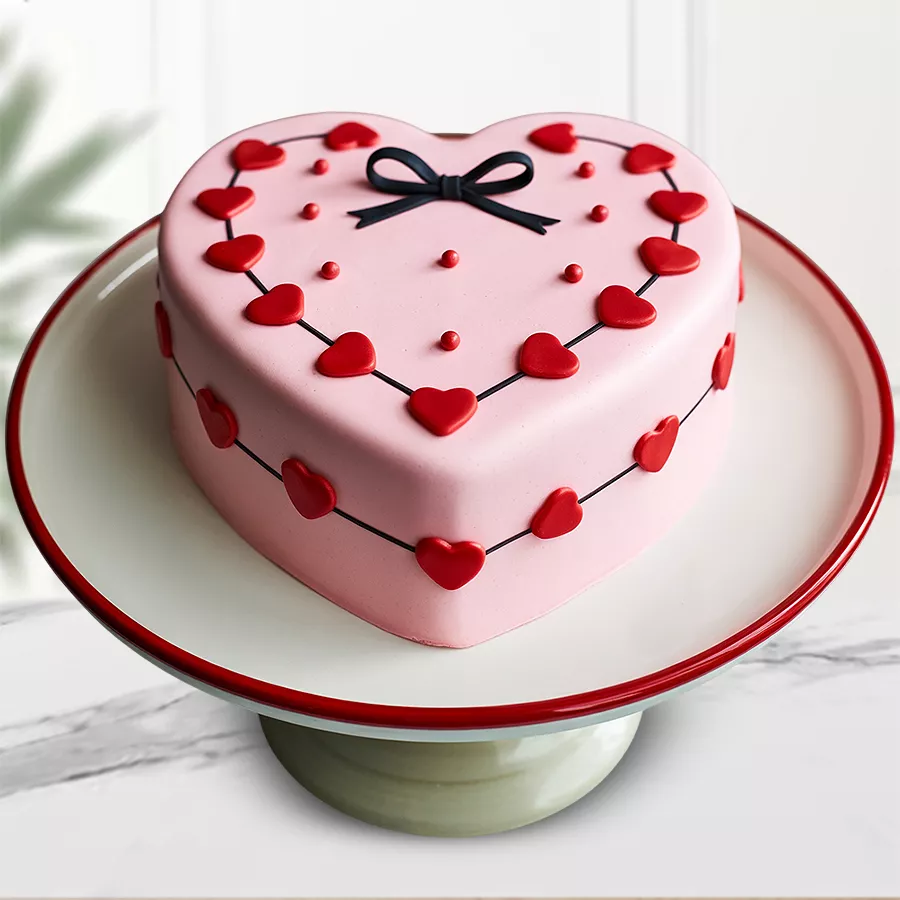 Heart-shaped Strawberry Fondant Cake with fondant hearts and white garnishing.