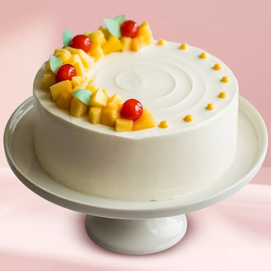 Heart-shaped pineapple cake topped with whipped cream, pineapple flower, and cherry.