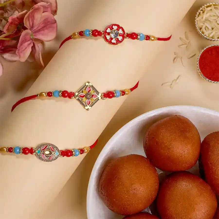 Traditional Kundan Rakhi trio with a 500g pack of Gulab Jamun, Roli, Tika, and Chawal on a festive background.