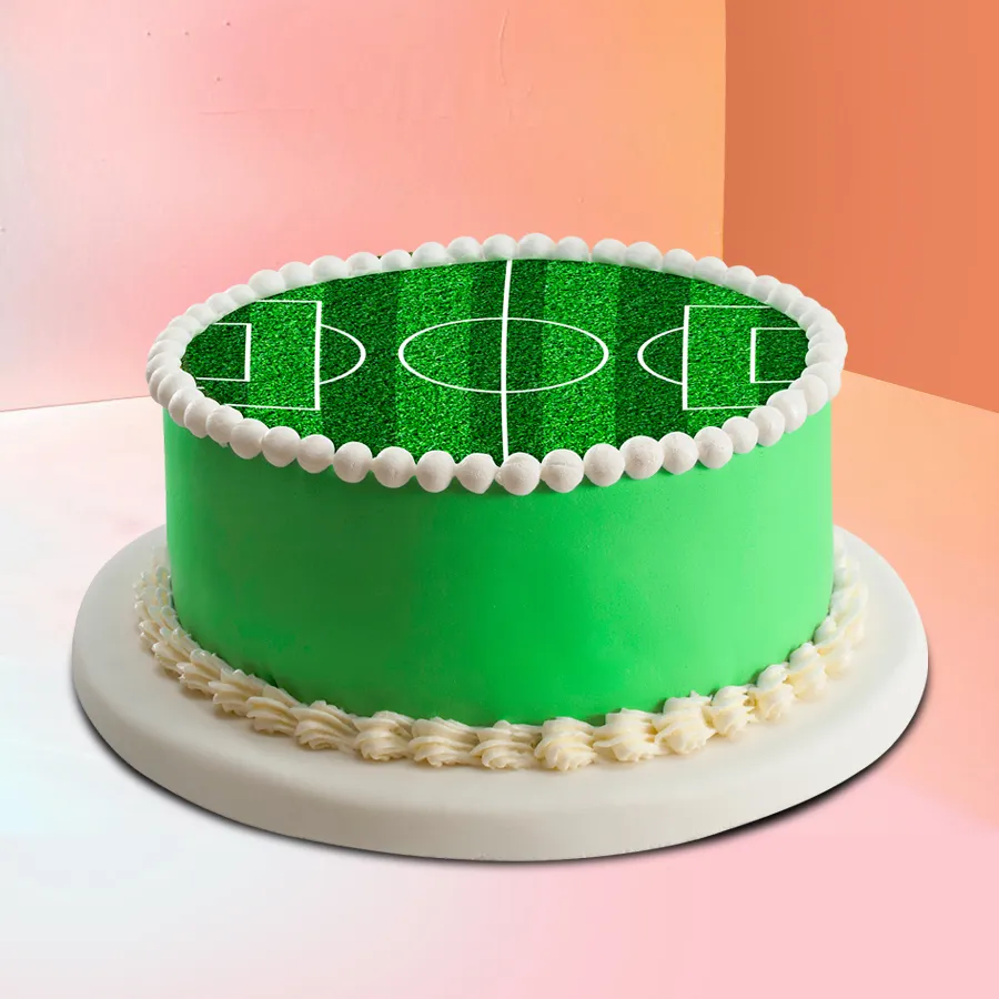A 1.5 kg football field cake designed for kids' celebrations, featuring vibrant green icing and football-themed decorations.