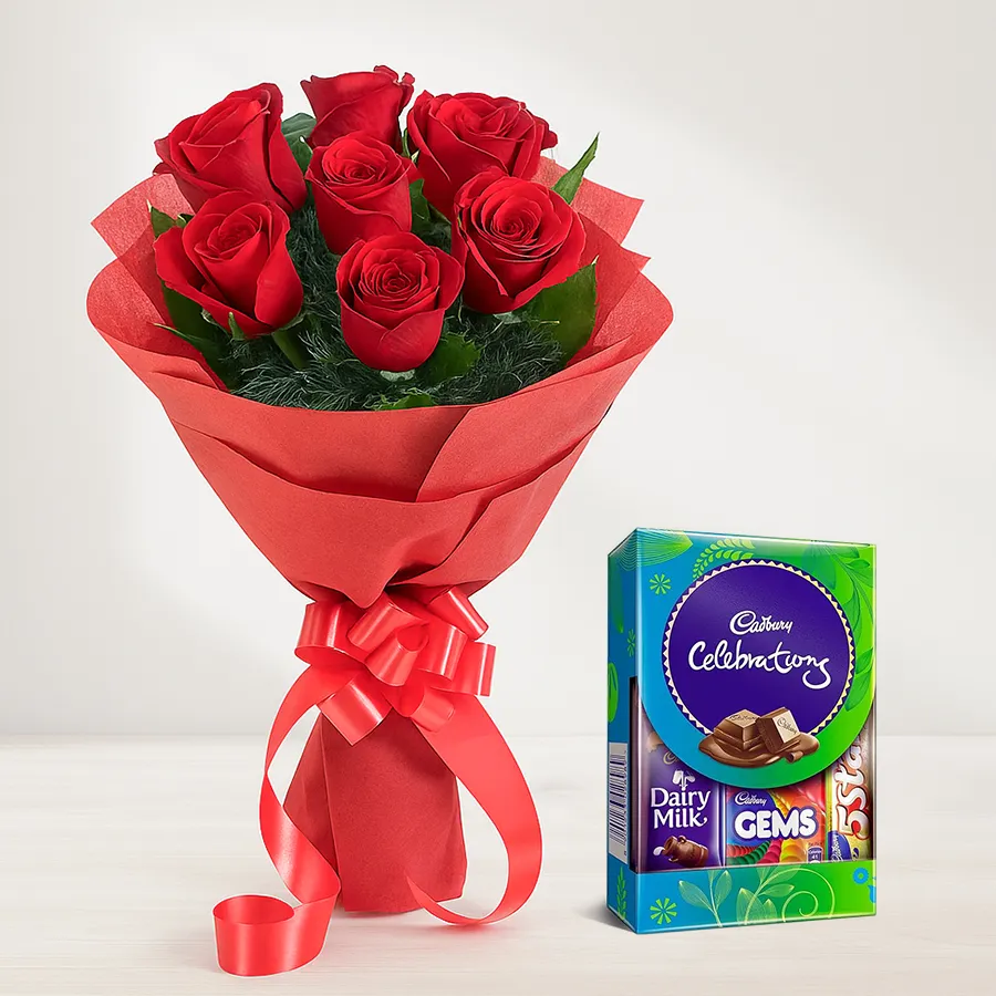 A stunning bouquet of red roses wrapped in tissue with a Cadbury Mini Celebrations Pack, perfect for gifting.