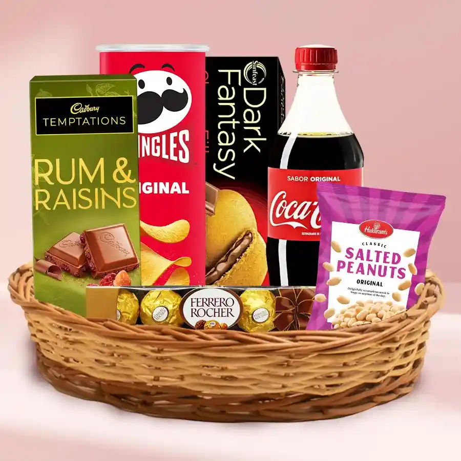 A vibrant gift basket filled with gourmet treats including chips, biscuits, peanuts, soda, chocolates, and a small basket.