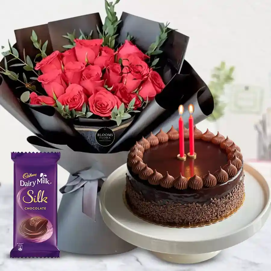 Combo of Cadbury Dairy Milk Silk chocolate, a chocolate cake, two candles, and a bouquet of 12 bright red roses.