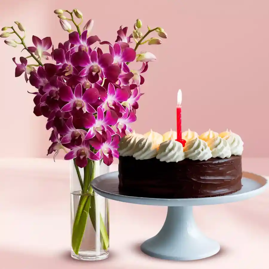 Delectable chocolate cake with candles and beautiful orchids in a vase, perfect for celebrations.