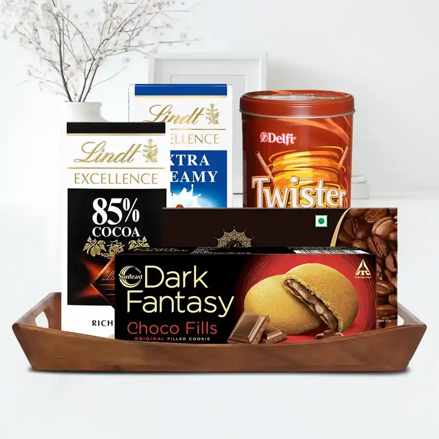 Luxury gift basket filled with imported chocolates including Toblerone, Lindt Excellence bars, Lindberg Coffee Chocolate, Dark Fantasy cookies, and Delfi Twisters in a reusable wooden tray.