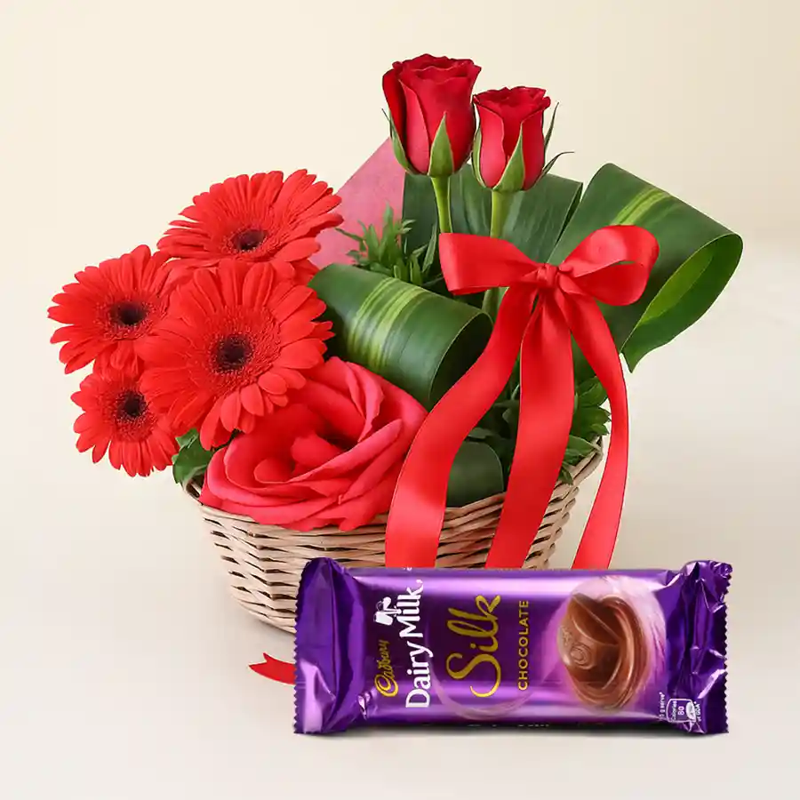 Assorted floral basket with red roses, gerberas, and Cadbury Silk chocolate.