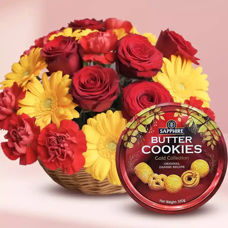A vibrant basket filled with red roses, yellow gerberas, red carnations, and a box of Sapphire Butter Cookies.