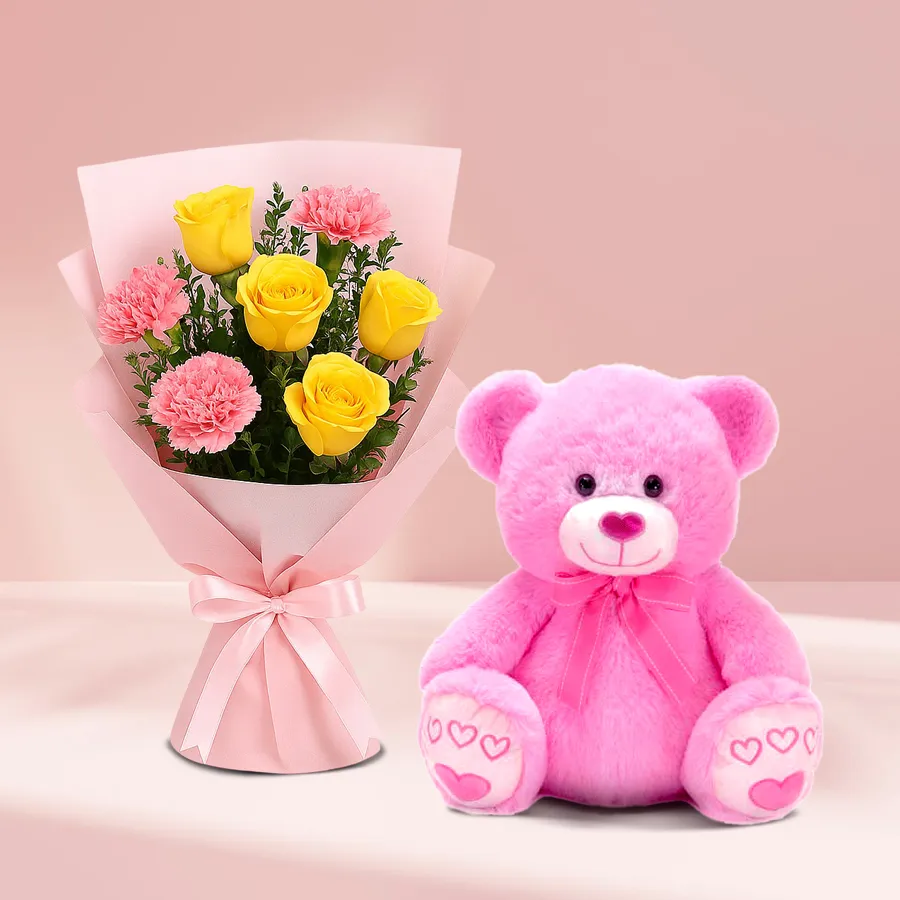 Vibrant yellow roses and pink carnations bouquet with a soft pink teddy bear.