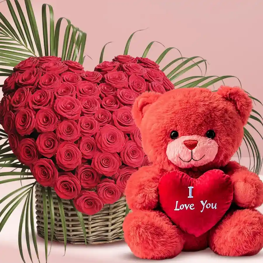 Heart-shaped bouquet of 50 red roses with a 12-inch red teddy holding a heart that says "I Love You" in an elegant arrangement.