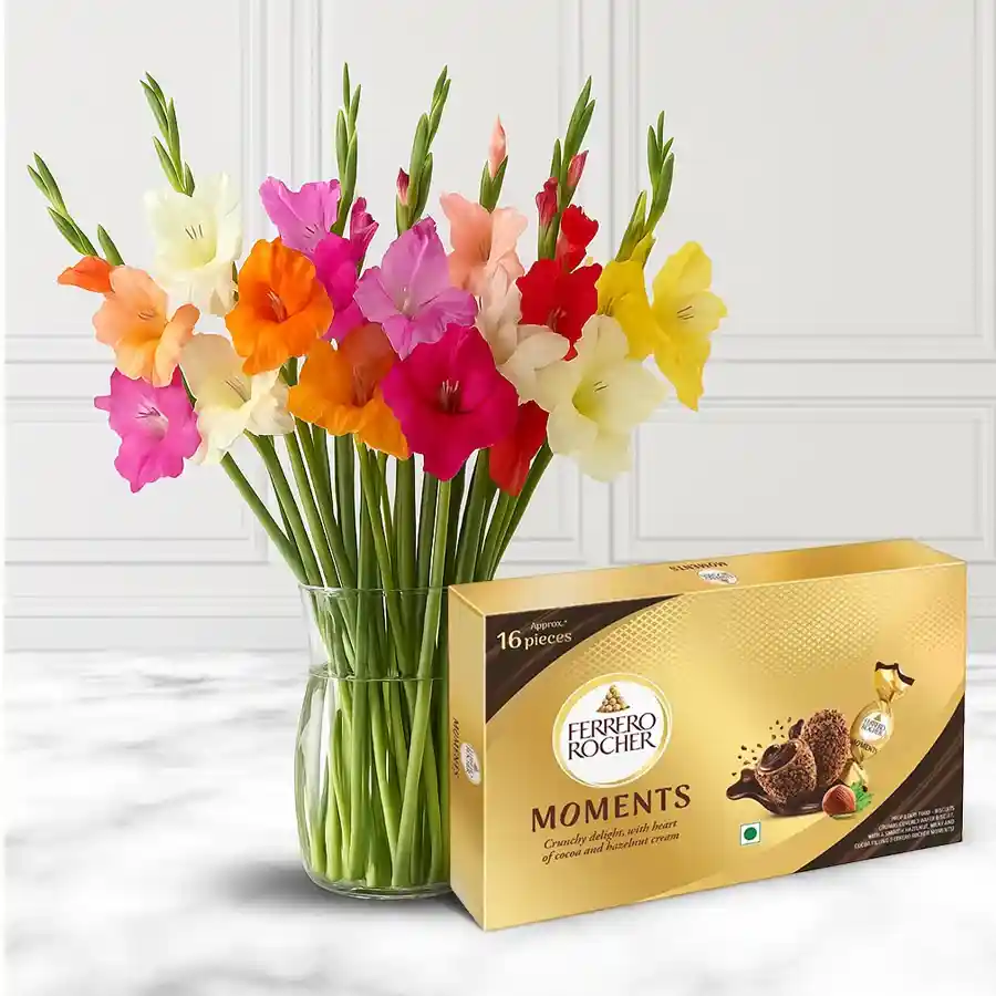 A beautiful arrangement of 10 assorted gladiolus in a glass vase accompanied by a box of 16 Ferrero Rocher Moments chocolates.