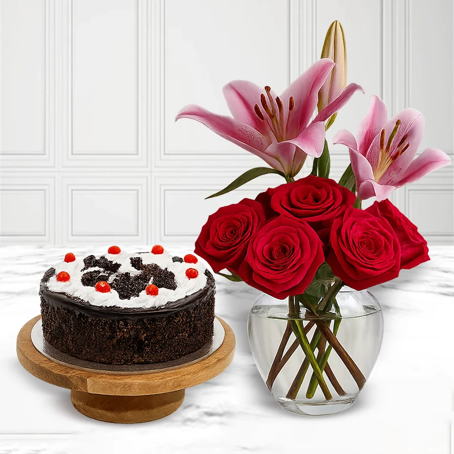Stunning Blossoms and Cake Delight Set featuring pink lilies, red roses, and a Black Forest Cake.