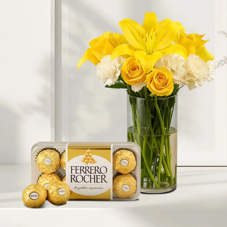 Arrangement of yellow roses, white carnations, and Asiatic lilies paired with Ferrero Rocher chocolates in a glass vase.