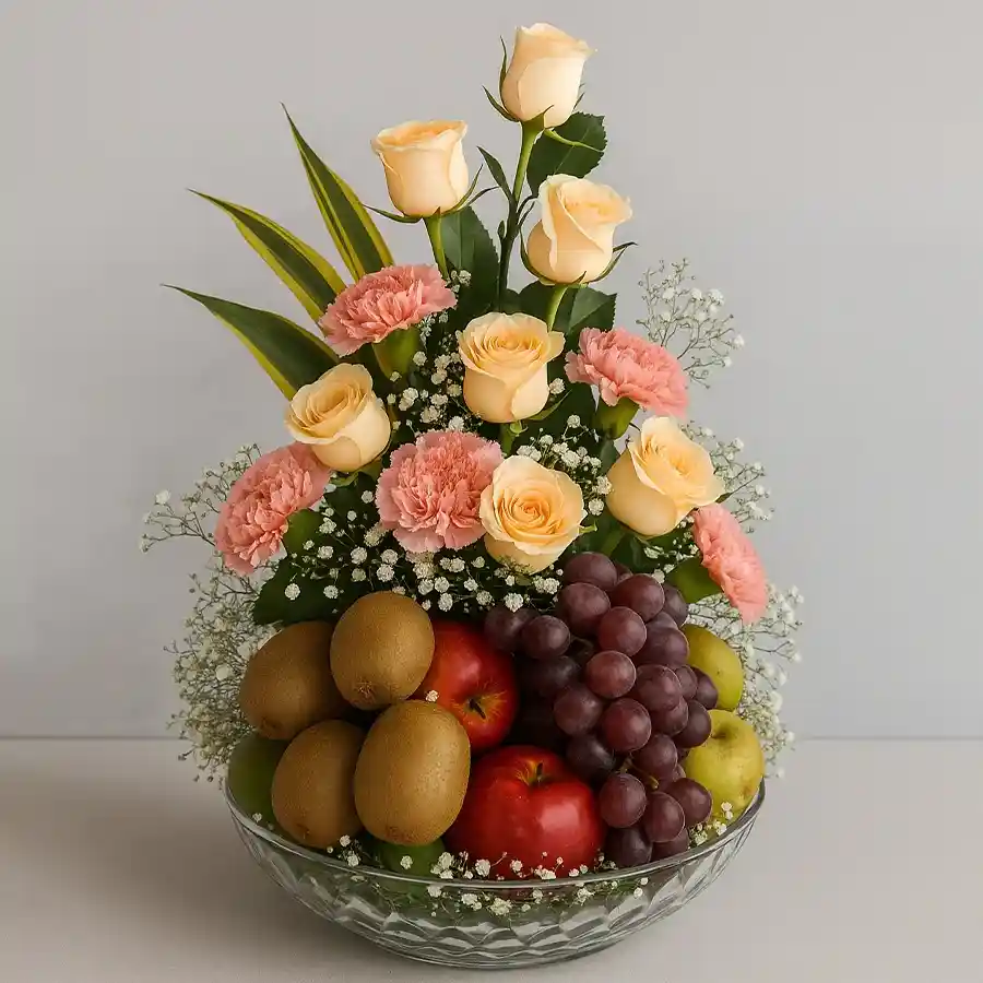 Beautiful arrangement of assorted fruits with orange roses and pink carnations in a glass vase.