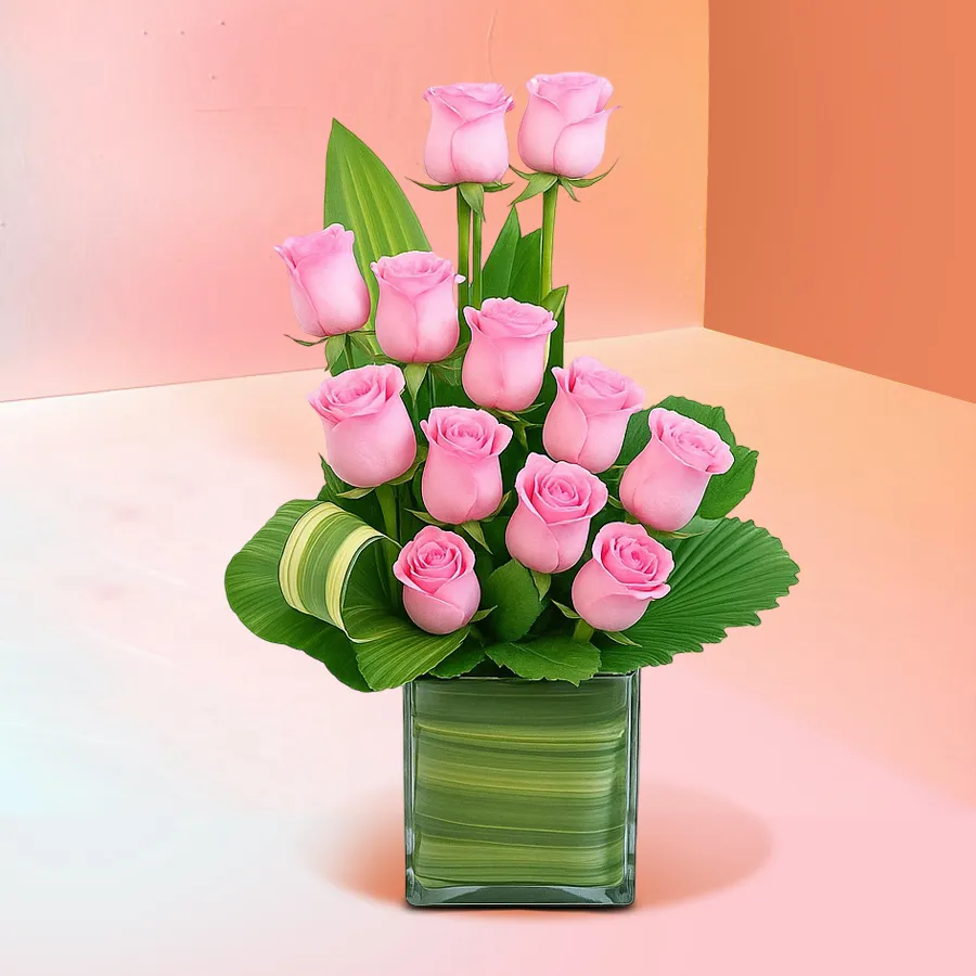 A beautiful arrangement of 12 pink roses in a medium round glass vase, ideal for gifting or home decor.