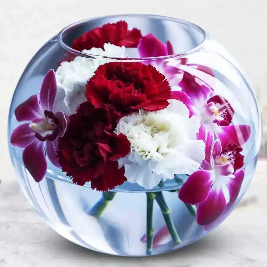 Vibrant Mother's Day floral arrangement with red and white carnations and orchids in a glass bowl.