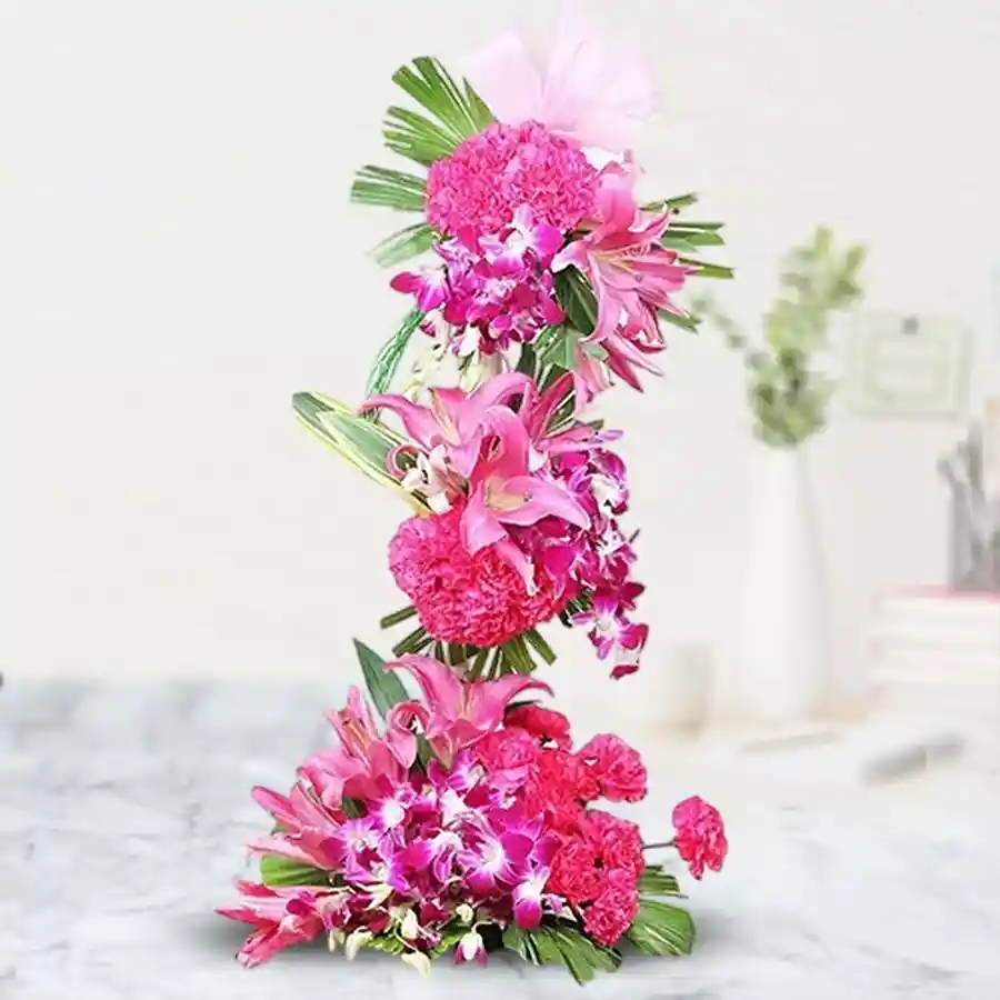 Striking 2-foot tall floral arrangement with pink carnations, oriental lilies, and orchids, perfect for Mother's Day.