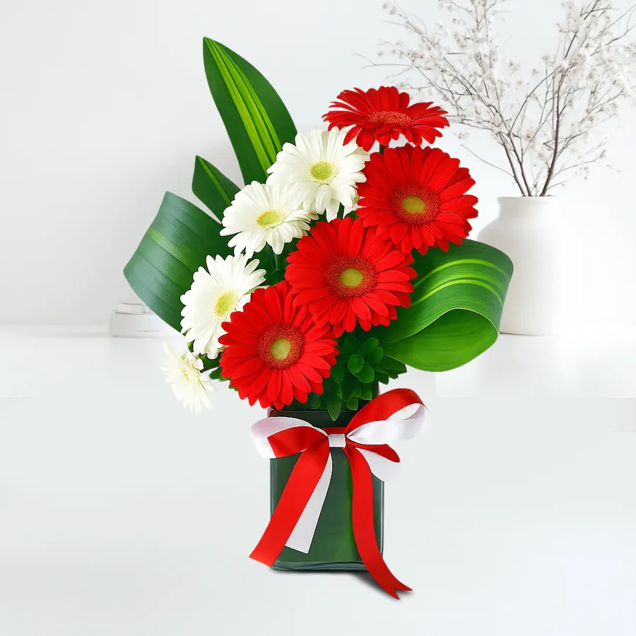 Radiant red gerbera and white daisy flower arrangement in a glass vase.