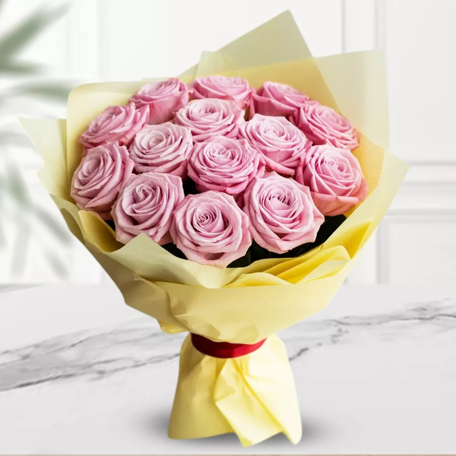 Bouquet of 12 pink roses wrapped in tissue, perfect for gifting.