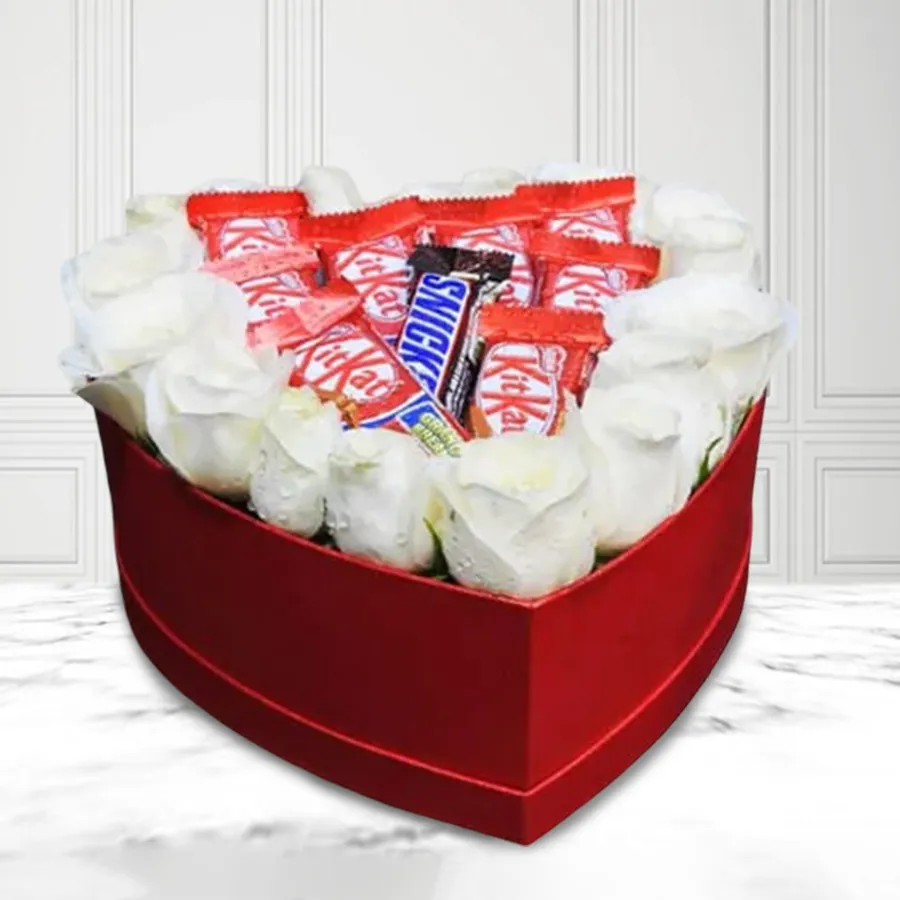 Heart-shaped box containing 16 white roses, 8 Nestlé KitKats, and a Snickers chocolate bar, perfect for expressing love.