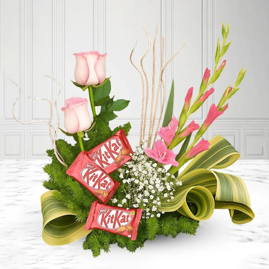 Beautiful arrangement of pink roses, gladiolus, and gypsy flowers with a Nestle Kit Kat chocolate bar.