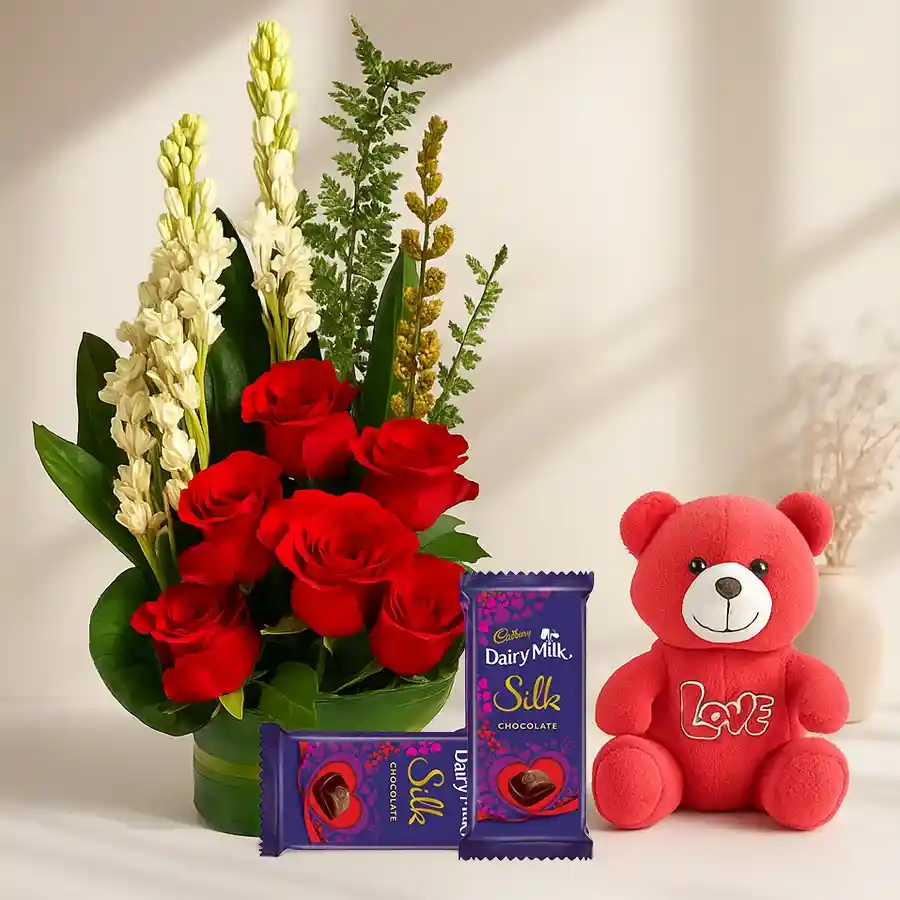 Whimsical combo featuring red roses, Rajnigandha flowers, a teddy bear, and Cadbury chocolates.