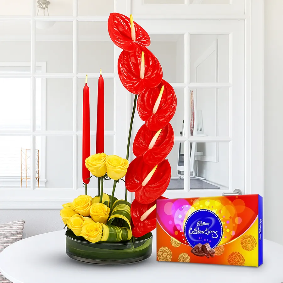 Colorful flower arrangement with yellow roses, red anthuriums, candles, and Cadbury Celebration chocolates.