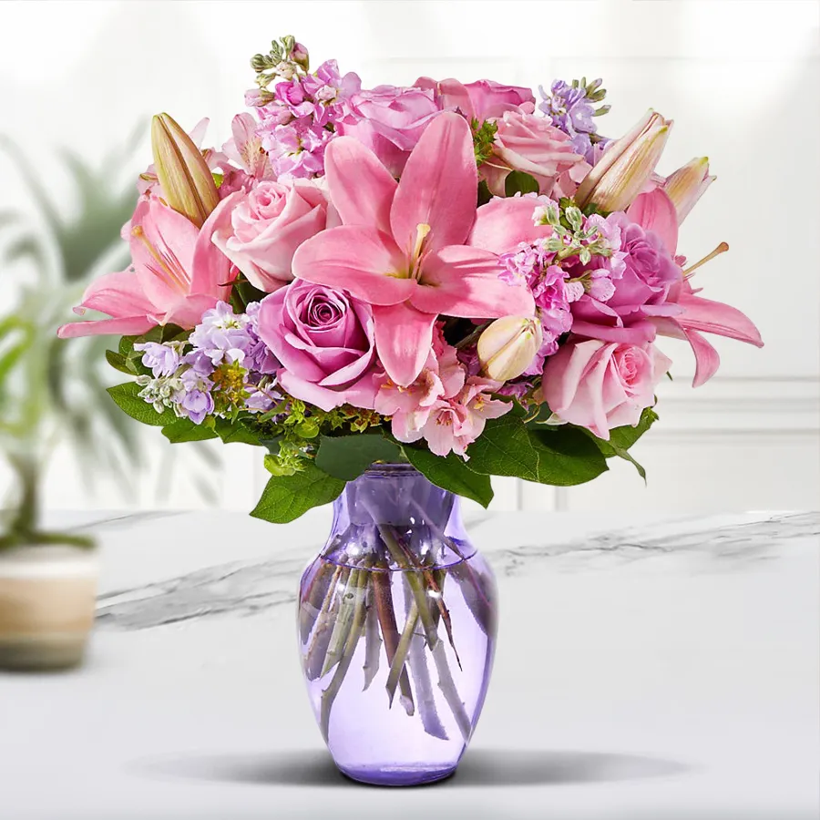 Elegant arrangement of pink lilies and roses in a glass vase.