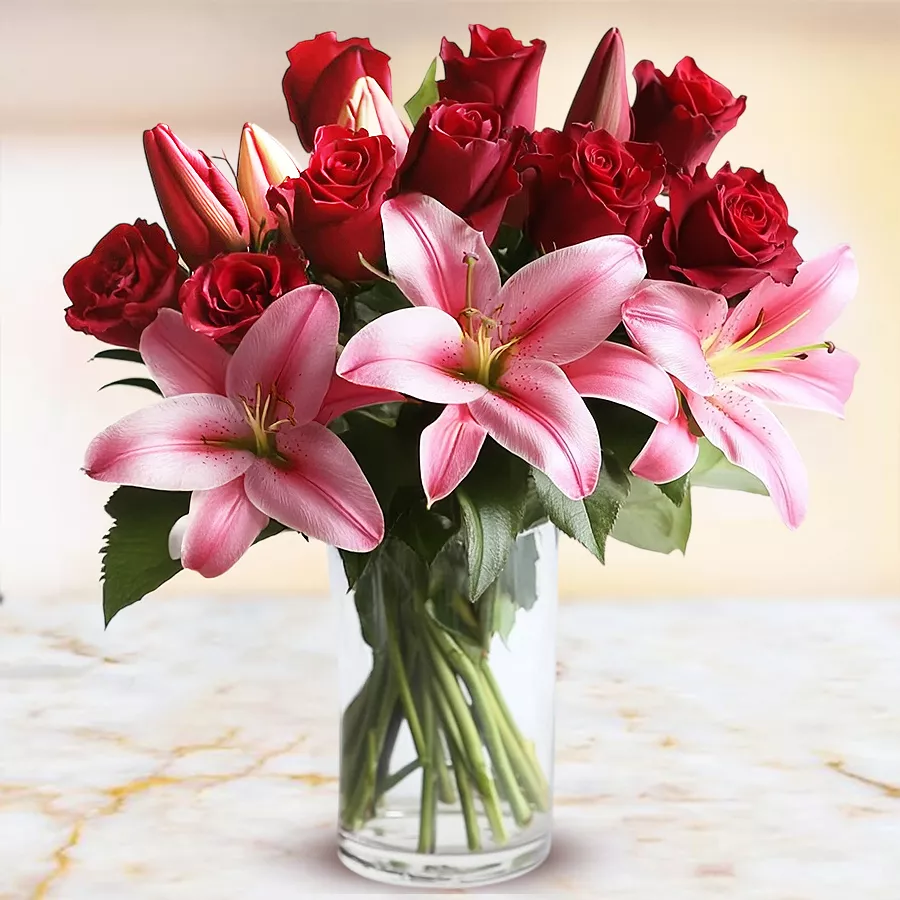 Elegant arrangement of red roses and pink lilies in a glass vase.