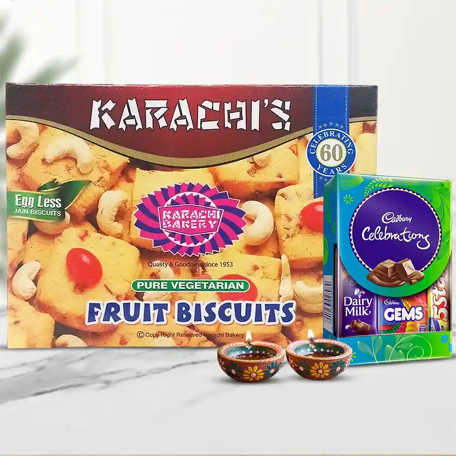 Fruit biscuits, assorted chocolates, and decorative diyas arranged in a festive gift hamper for Diwali celebration.