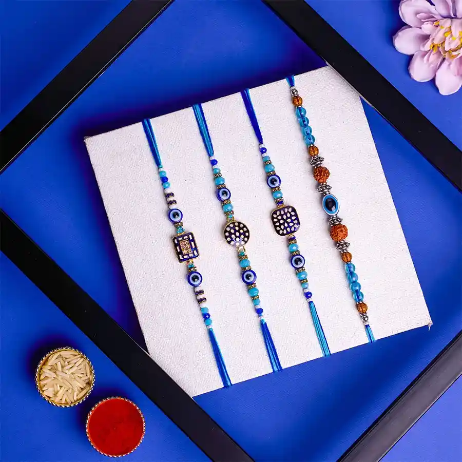Four Evil Eye Rakhis set with vibrant threads and charms, including ritual essentials and a message card.